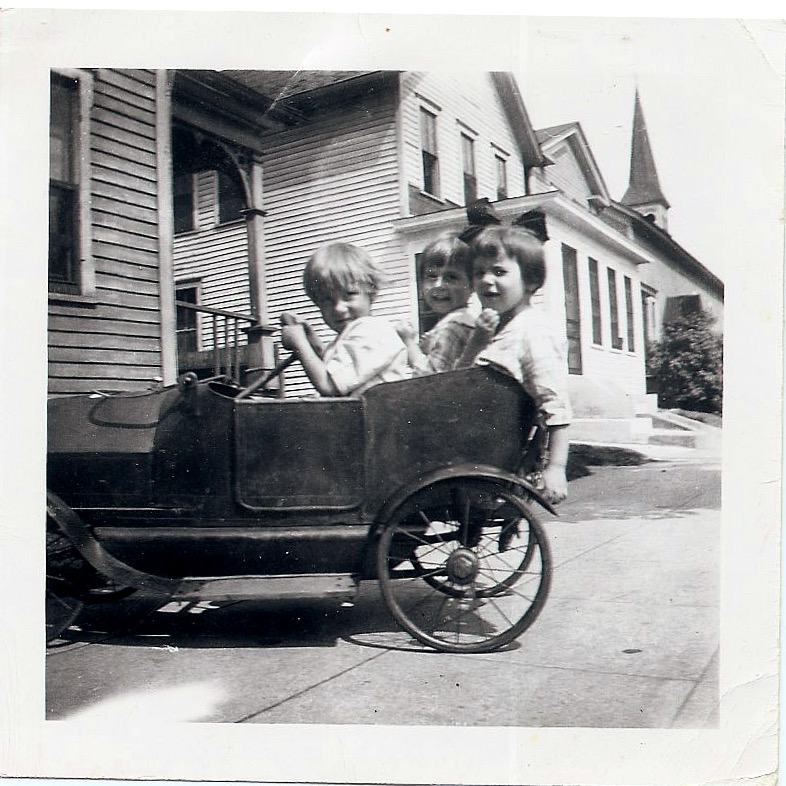 Three kids in toy car, 1919
